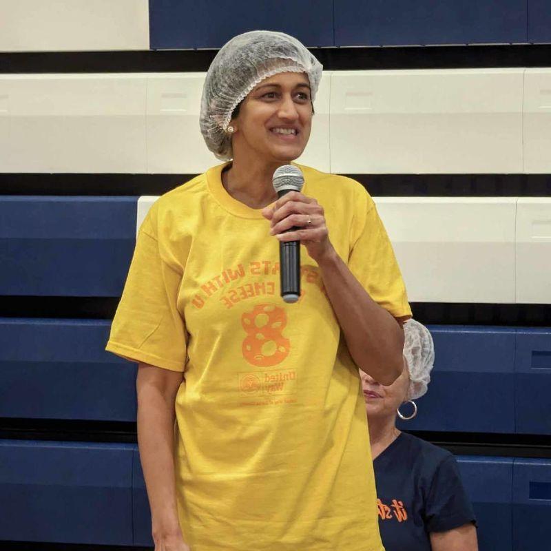 Pyati wearing hair net holding microphone speaking to crowd